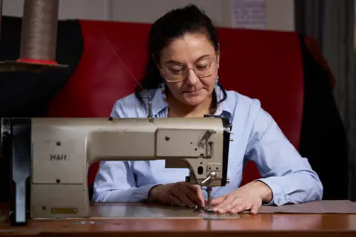 Magali Billy sur la machine industrielle, héritée de l'atelier de confection artisanale de sa grand-mère. Travail d'assemblage d'une doublure en Alcantara.