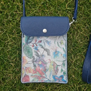 Pochette artisanale en cuir bleu marine et blanc à motifs fleuris colorés, portée en bandoulière.