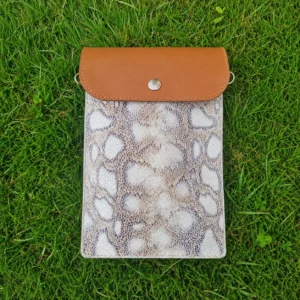 Pochette artisanale en cuir camel et beige à motifs jungle, portée en bandoulière.