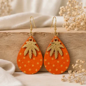 Boucles d'oreilles artisanales en cuir orange décoré de petites étoiles dorées avec feuille métallique dorée.