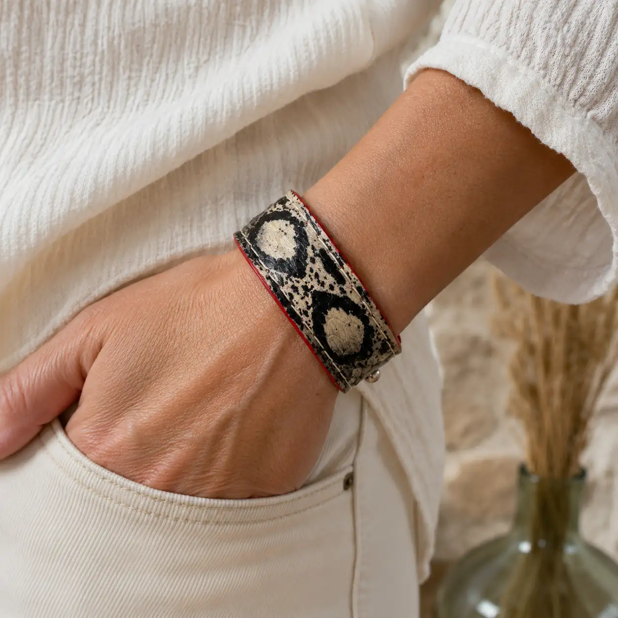 Bracelet artisanal en cuir de serpent noir et beige porté avec une tenue élégante