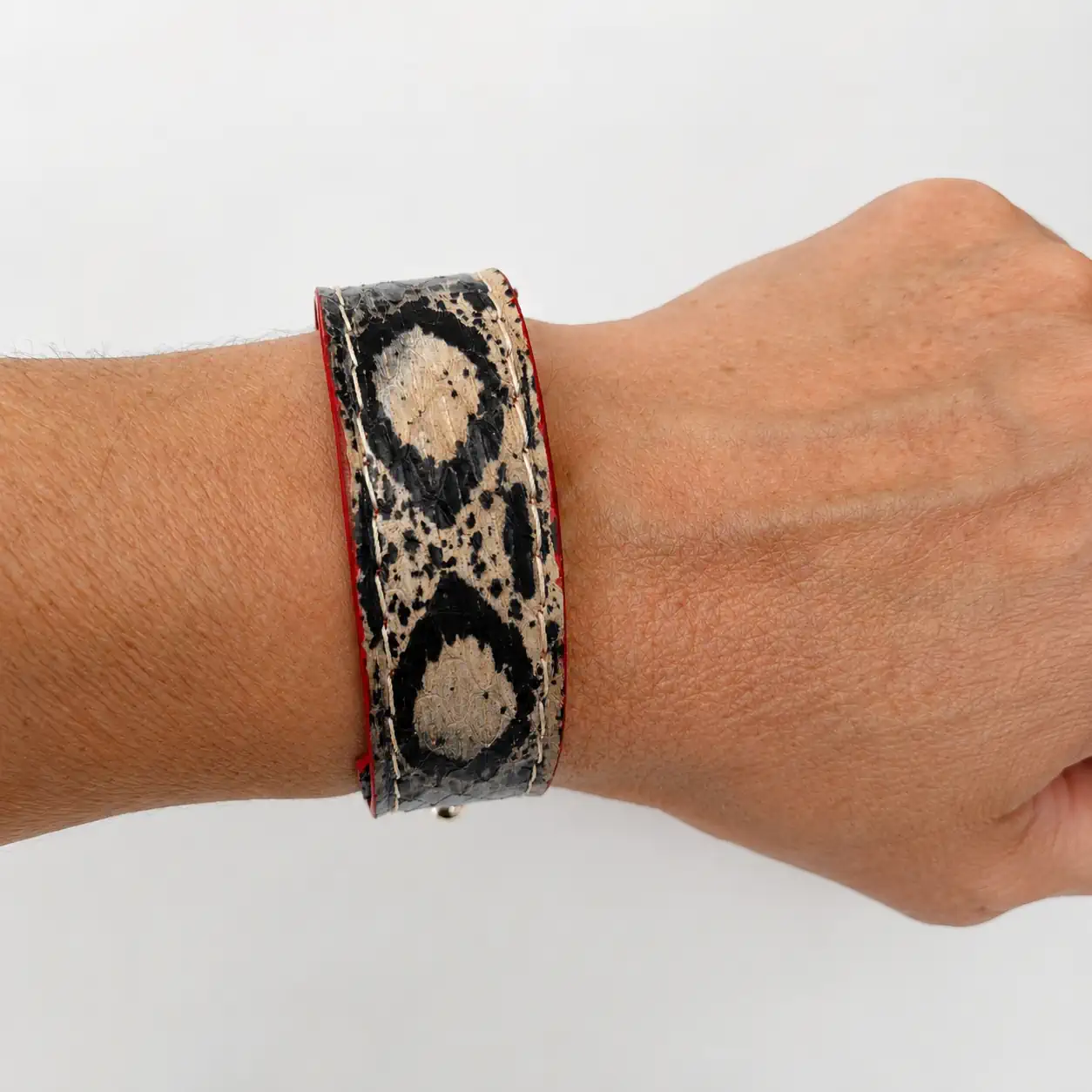 Bracelet artisanal en cuir de serpent noir et beige porté au poignet